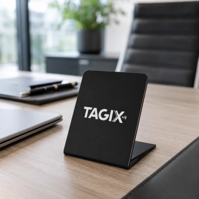 Chevalet NFC TAGIX noir posé sur un bureau professionnel moderne, avec ordinateur portable, carnet et fauteuil en arrière-plan.