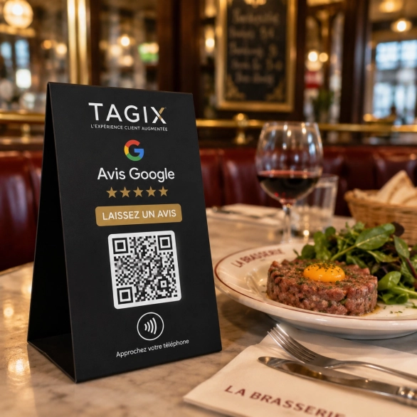 Chevalet TAGIX pour avis Google avec QR code et NFC posé sur une table de brasserie à côté d’un plat et d’un verre de vin